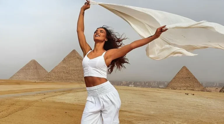 Tourist with white cloth celebrating at the Pyramids of Giza, discovering iconic wonders.